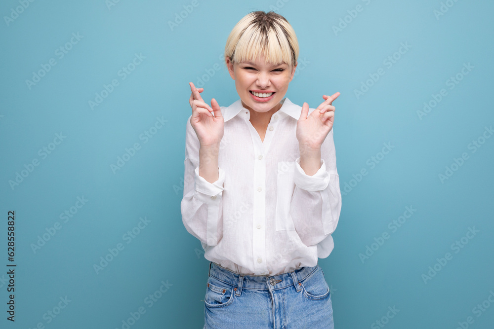 young pretty smart blond female student woman in white shirt crossed her fingers and hopes for good luck in the exam against background with copy space young pretty smart blond female student woman in white shirt crossed her fingers and hopes for good luck in the exam against background with copy space