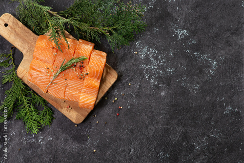 Salmon. Fresh raw salmon fish fillet with cooking ingredients, herbs and lemon on black background