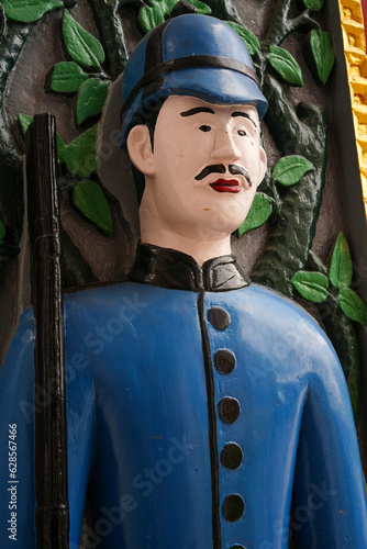 Wat Ratchabophit, Bangkok, Thailand, completed in 1869. On a wooden door is a carved figure of a soldier dressed in blue standing guard at the entrance to the church. for tourists to see and take pict