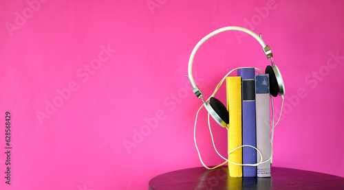 Obraz na plátně audio book concept with stack of books and vintage headphones on pink  backgroun