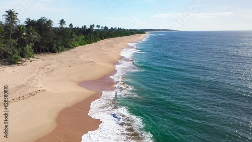 4K drone flying UP footage of ocean waves rolling onto sandy beach with white foam. Environment, exotic places, summer holiday concept. Tangalle, Sri Lanka. photo
