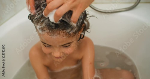 Bath Time Delight: Creating Cherished Memories as a Loving Mother Gently Washes Her Child's Hair with Bubbles of Joy. High quality 4k footage