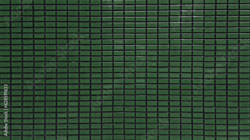 close up dark green colored mosaic wall tiles. ceramic tiles in rectangle pattern, emerald colored. vintage green mosaic kitchen wall pattern used as background.