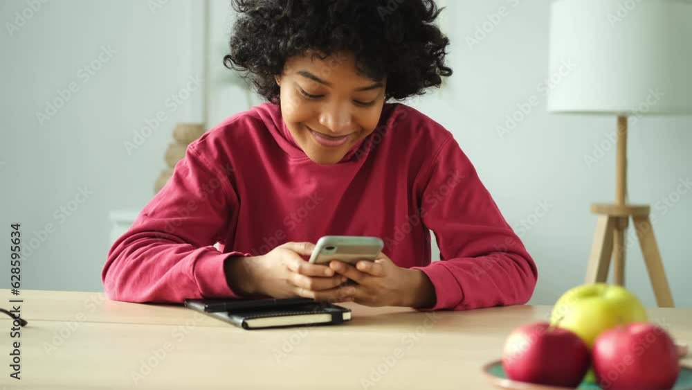 African girl holding smartphone touch screen typing scroll page at home. Woman with cell phone surfing internet using social media apps playing game. Shopping online Internet news cellphone addiction African girl holding smartphone touch screen typing scroll page at home. Woman with cell phone surfing internet using social media apps playing game. Shopping online Internet news cellphone addiction