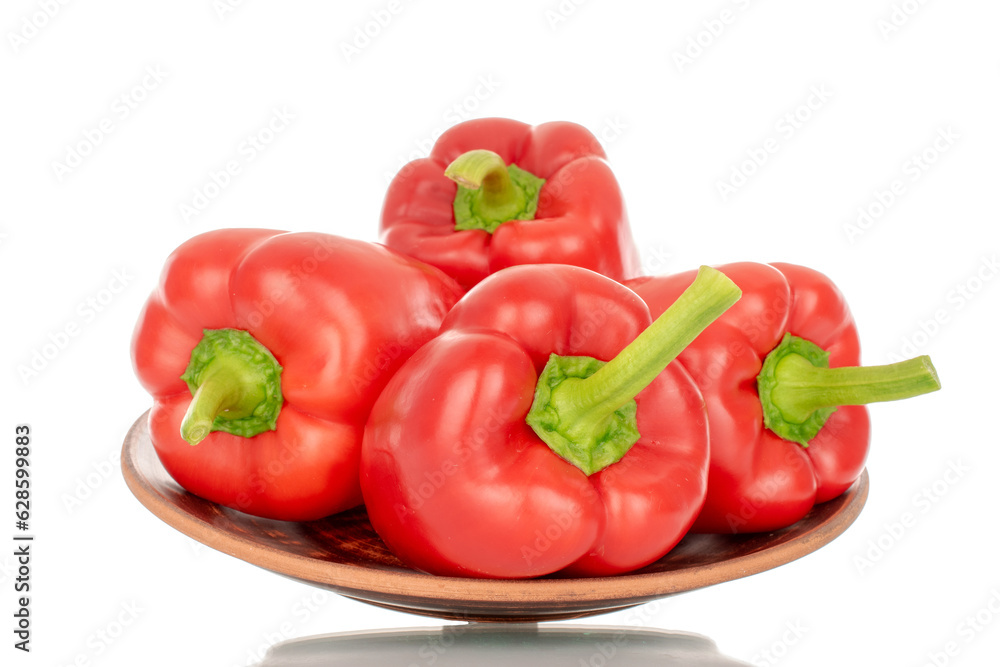 Several red bell peppers on a clay plate, macro, isolated on white background. Several red bell peppers on a clay plate, macro, isolated on white background.