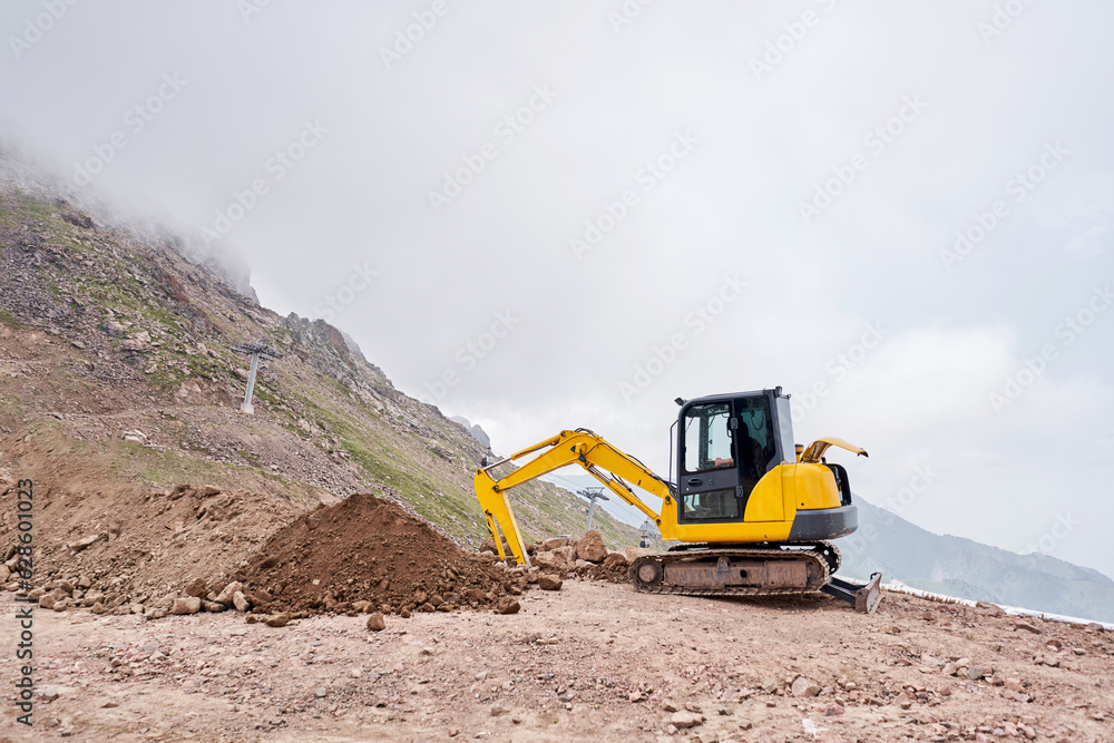 Excavator works in the highlands. Makes a trench for communications. water and electricity. in the gorge of the mountains. repair and expansion of a road Excavator works in the highlands. Makes a trench for communications. water and electricity. in the gorge of the mountains. repair and expansion of a road