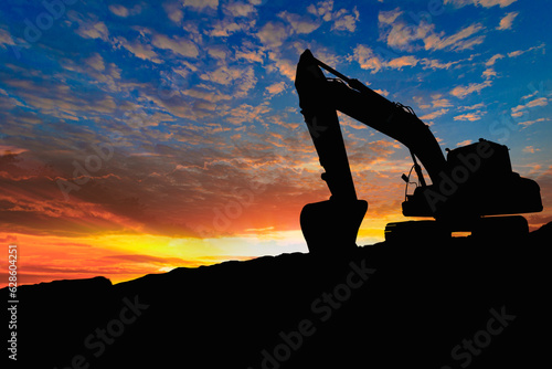 Crawler excavators silhouette are digging the soil in the construction site on the sunset background