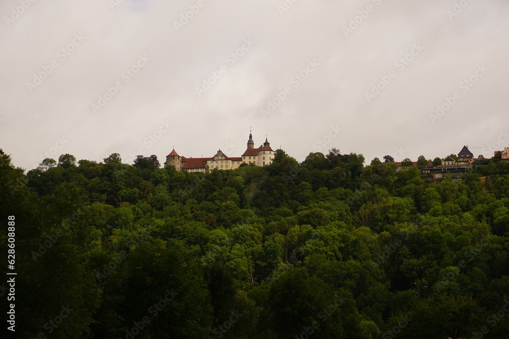 Kirche Schloss auf einem Berg liegend vor dunkelgrünen Bäumen