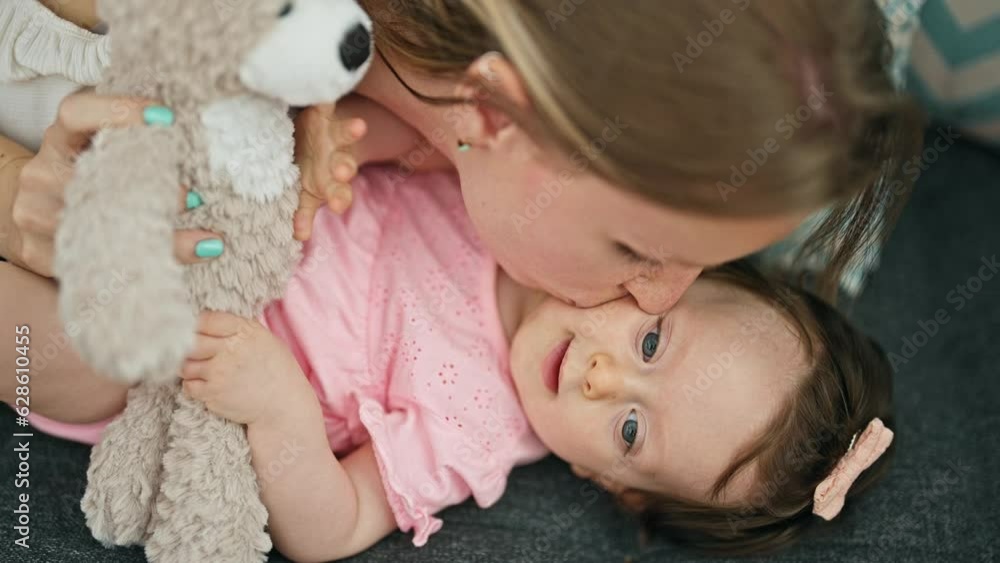 Mother and daughter lying on sofa playing with teddy bear kissing at home Mother and daughter lying on sofa playing with teddy bear kissing at home