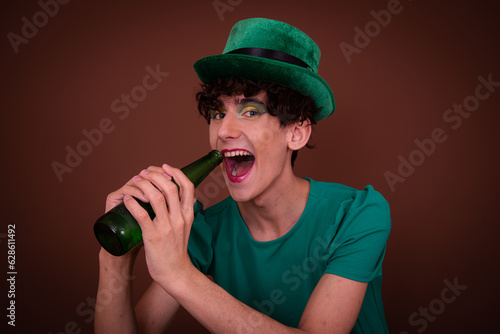 Drag Queen on St. Patrick's Day in a green hat drinks green beer.