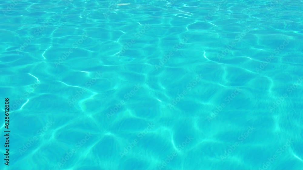 Transparent Azure Turquoise Blue Water in Glare and Sunbeams in the Ocean Sea Swimming Pool. Waves Ripples on Water in Sunlight. Surface of the Water in the Pool Sea Ocean. Background Vacation Travel. Transparent Azure Turquoise Blue Water in Glare and Sunbeams in the Ocean Sea Swimming Pool. Waves Ripples on Water in Sunlight. Surface of the Water in the Pool Sea Ocean. Background Vacation Travel.