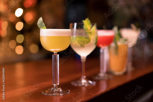 Fotografie Close up of cocktails of different colors in different glasses standing on the b