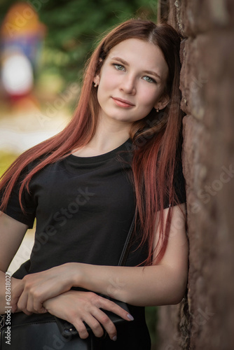 Portrait of a beautiful young red-haired girl in jeans and a dark-colored T-shirt.