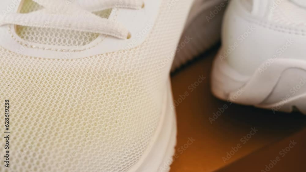 Close-up, Two Different White Pairs of Perforated Sneakers. Shoe toe. Texture, mesh, holes, fabric structure. Black background, blurred motion. Laces. Female shoes for fitness. Macro. Sport concept. Close-up, Two Different White Pairs of Perforated Sneakers. Shoe toe. Texture, mesh, holes, fabric structure. Black background, blurred motion. Laces. Female shoes for fitness. Macro. Sport concept.