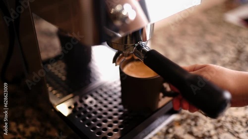 Espresso machine. Slow motion. Female hand picks up a gray cup of fresh coffee. 