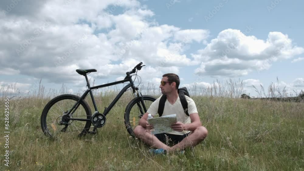 a cyclist with a backpack stopped and looks at the map of the area.Healthy lifestyle.Sports outside a cyclist with a backpack stopped and looks at the map of the area.Healthy lifestyle.Sports outside