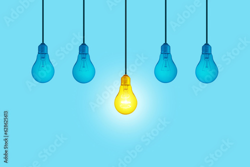 Blue light bulbs with glowing one yellow different light bulb idea hanging on blue background. Think creatively concept. New Creative Idea. Brainstorm