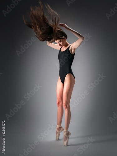 Young slender model-looking dancer with long hair in black tight-fitting dancewear in action