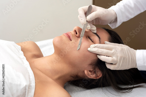 young woman on a table in a beauty center performing a beauty treatment for facial skin with the dermaplaning technique