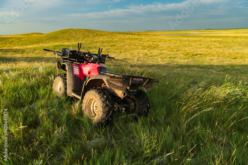 A four wheeler sits in tall grass in a South Dakota prairie at sunset photo