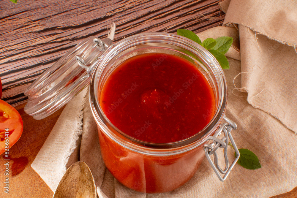 Fresh Tomato Sauce in a Glass Jar in a wooden table in top view Fresh Tomato Sauce in a Glass Jar in a wooden table in top view