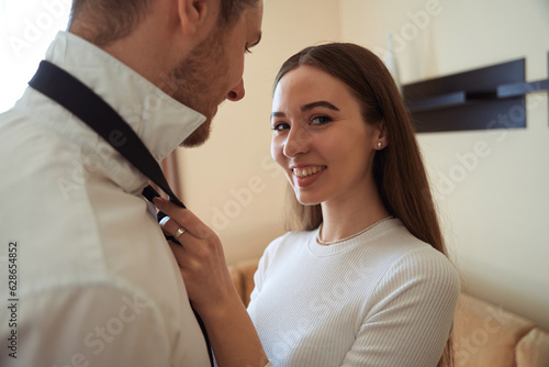 Smiling woman helping dress to male in the hotel