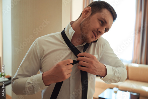 Man getting dressed before job and talking on phone