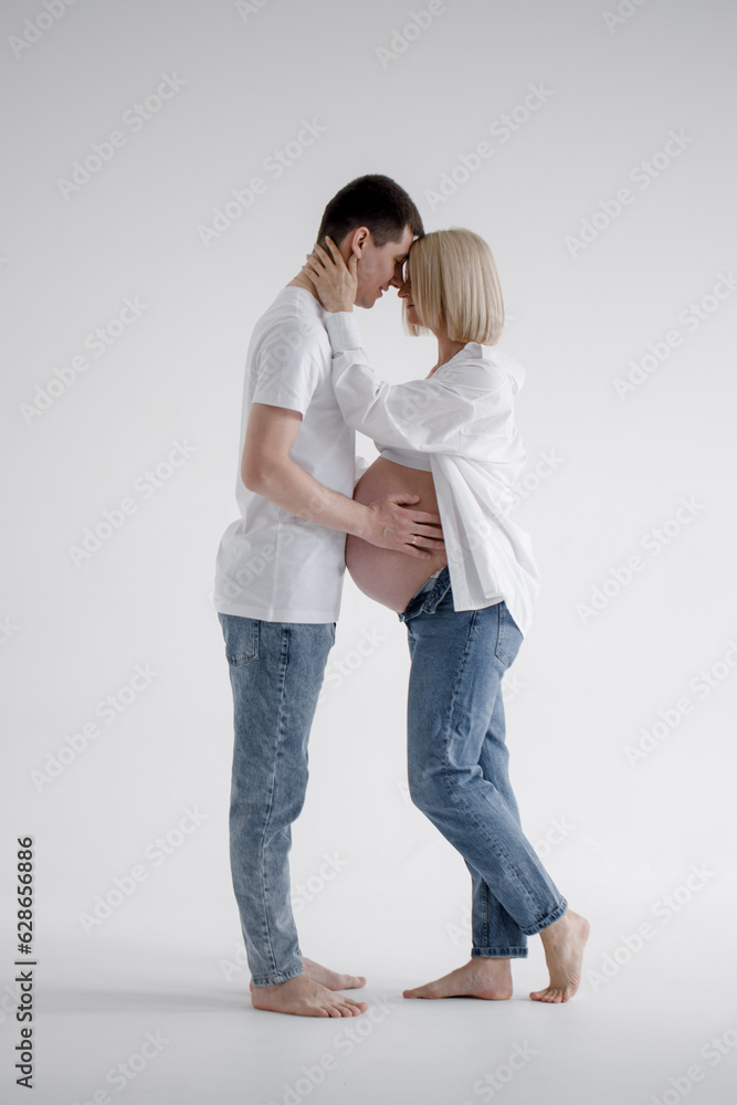 Family couple. A pregnant blond woman of Caucasian appearance is having sex with her husband, they look at each other and gently touch their stomachs. They wear jeans and a white T-shirt. Family couple. A pregnant blond woman of Caucasian appearance is having sex with her husband, they look at each other and gently touch their stomachs. They wear jeans and a white T-shirt.