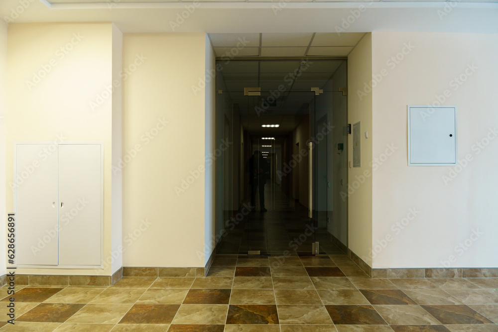 A bright empty space. An empty spacious office hall, clean white walls and bright lights. Window and door in the center of the room. A bright empty space. An empty spacious office hall, clean white walls and bright lights. Window and door in the center of the room.