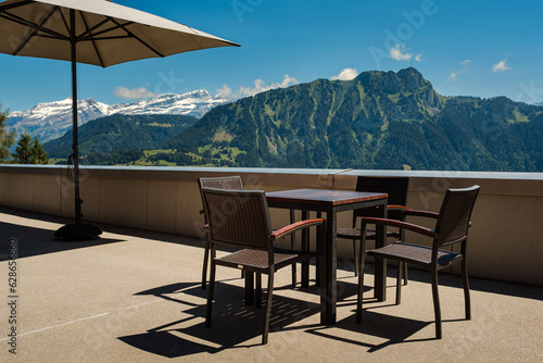 Empty terrace with a table, chairs and umbrella. Stunning view on the Diablerets massif in the Swiss Alps. Leysin, Vaud, Switzerland