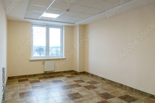A bright empty space. An empty spacious office hall  clean white walls and bright lights. Window and door in the center of the room.