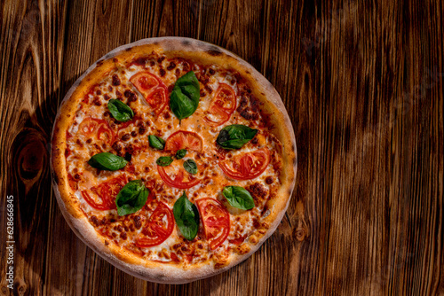 Delicious fragrant pizza with mozzarella, tomatoes and basil with tomato sauce on woden background. Top view