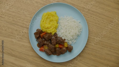 top view of a dish of rice, cassava puree and steak bites  rotating