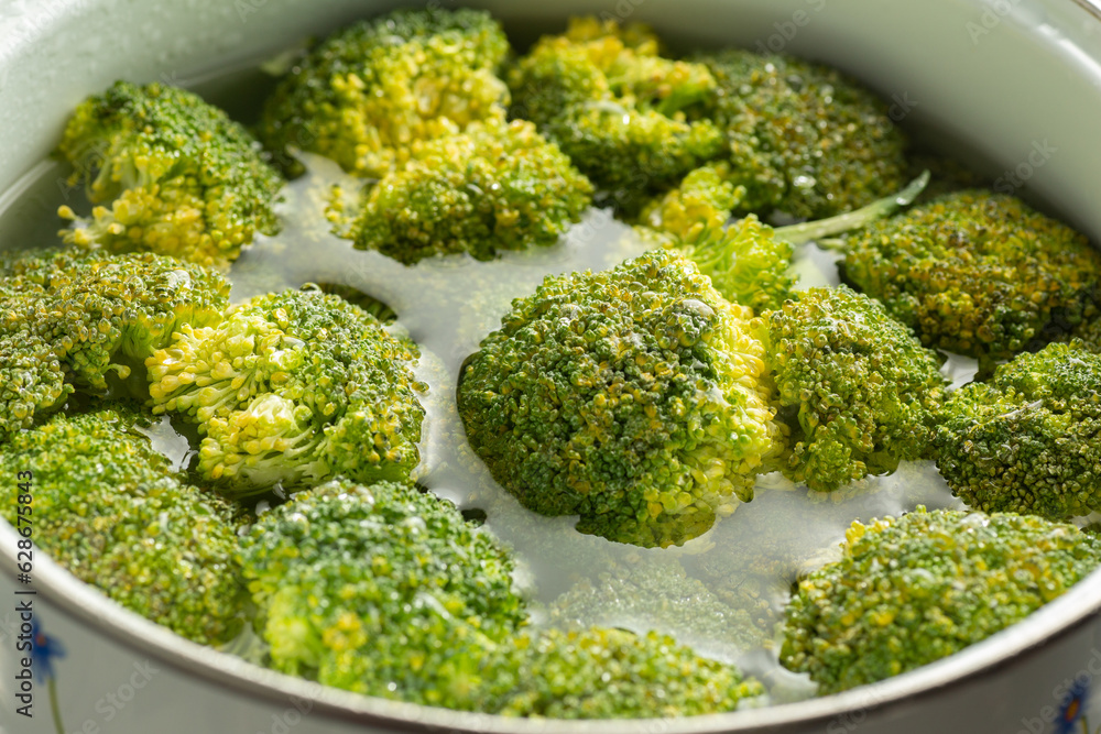 delicious green organic broccoli cut into a white pot with water on top of the cooking pot (Brocolis Organico) delicious green organic broccoli cut into a white pot with water on top of the cooking pot (Brocolis Organico)