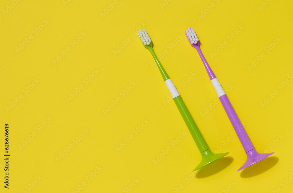 Two plastic toothbrushes on a yellow background, oral hygiene Two plastic toothbrushes on a yellow background, oral hygiene