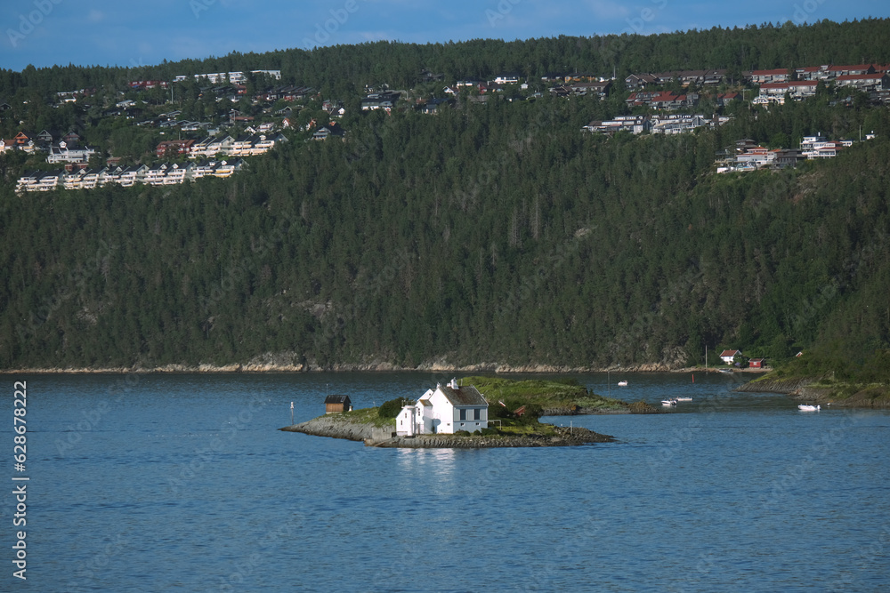 Obraz premium Landestypische Ferienhäuser an einem Ufer des Oslofjords, in der Nähe der norwegischen Hauptstadt Oslo, mit Haus auf einer Miniinsel, Natur, blauer Himmel und Copy space