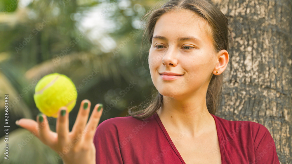 Fototapeta premium Young woman twirling a tennis ball in her hand
