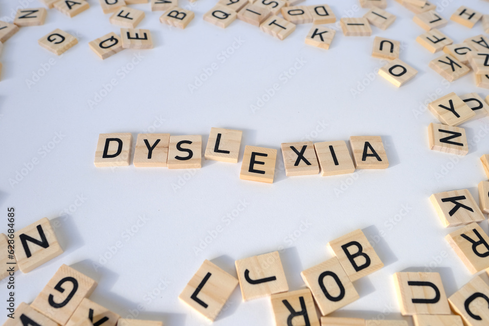 Obraz premium close-up wooden alphabet blocks, DYSLEXIA word on white background, dyslexia awareness, help with reading, learning difficulties, human brain development, literacy problems concept