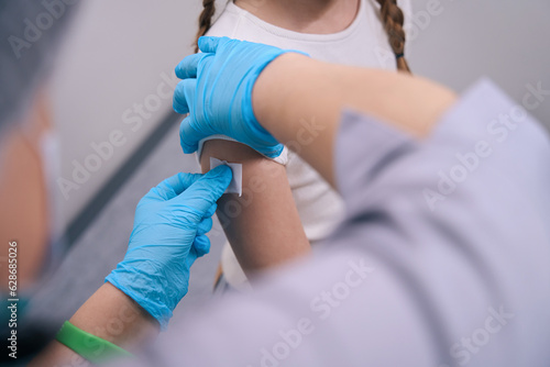 Nurse glues a patch after an injection on girls hand