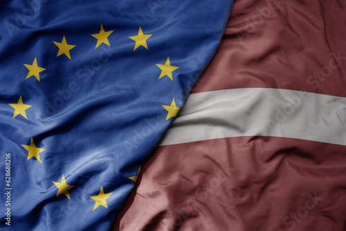 big waving realistic national colorful flag of european union and national flag of latvia .