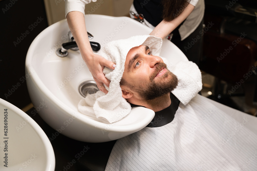 Female barber washes the head of client at special sink Female barber washes the head of client at special sink