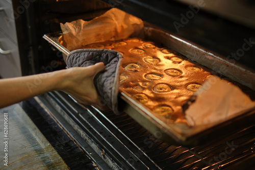 Cooking banana pie in the oven. A hand holds a hot baking sheet with a tongs