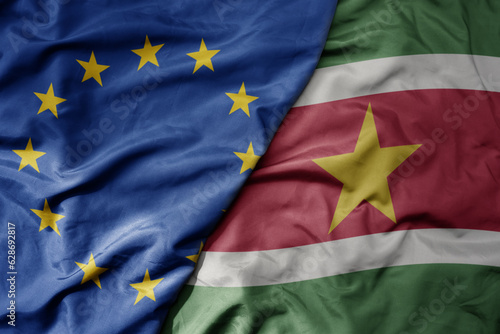 big waving realistic national colorful flag of european union and national flag of suriname .