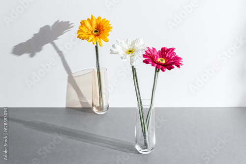 Fototapeta Naklejka Na Ścianę i Meble -  arrangement of vibrant flowers in unique glass vases placed a top a modern, grey table surface