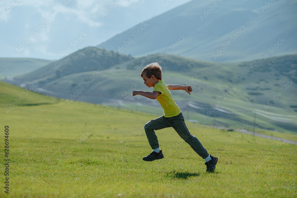 Boy running fast on a green meadow in the mountains Boy running fast on a green meadow in the mountains
