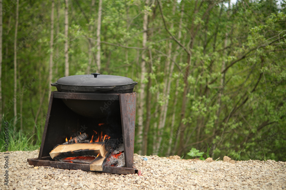 Cooking food in a cast-iron cauldron on fire, in nature Cooking food in a cast-iron cauldron on fire, in nature