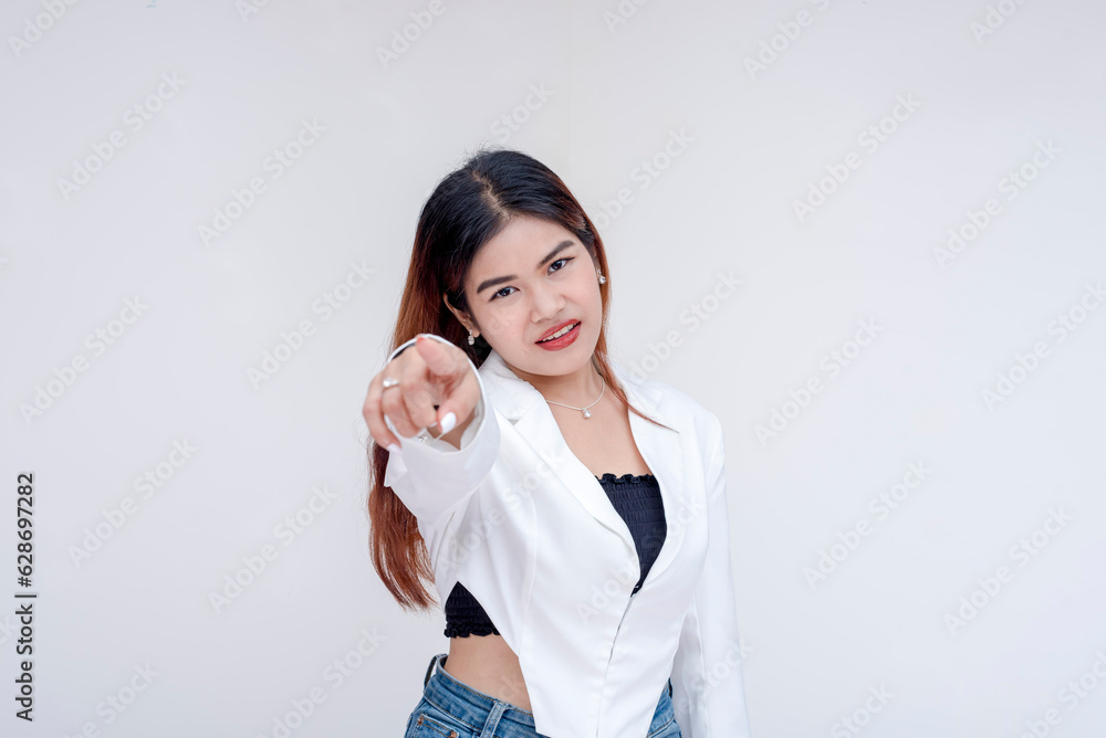 A serious young woman staring while pointing at the camera with her head tilted. Isolated on a white background. A serious young woman staring while pointing at the camera with her head tilted. Isolated on a white background.
