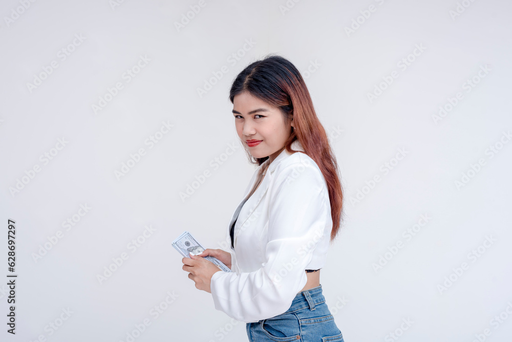 A teasing and taunting young woman smirking at the camera while holding her money away. Isolated on a white background. A teasing and taunting young woman smirking at the camera while holding her money away. Isolated on a white background.