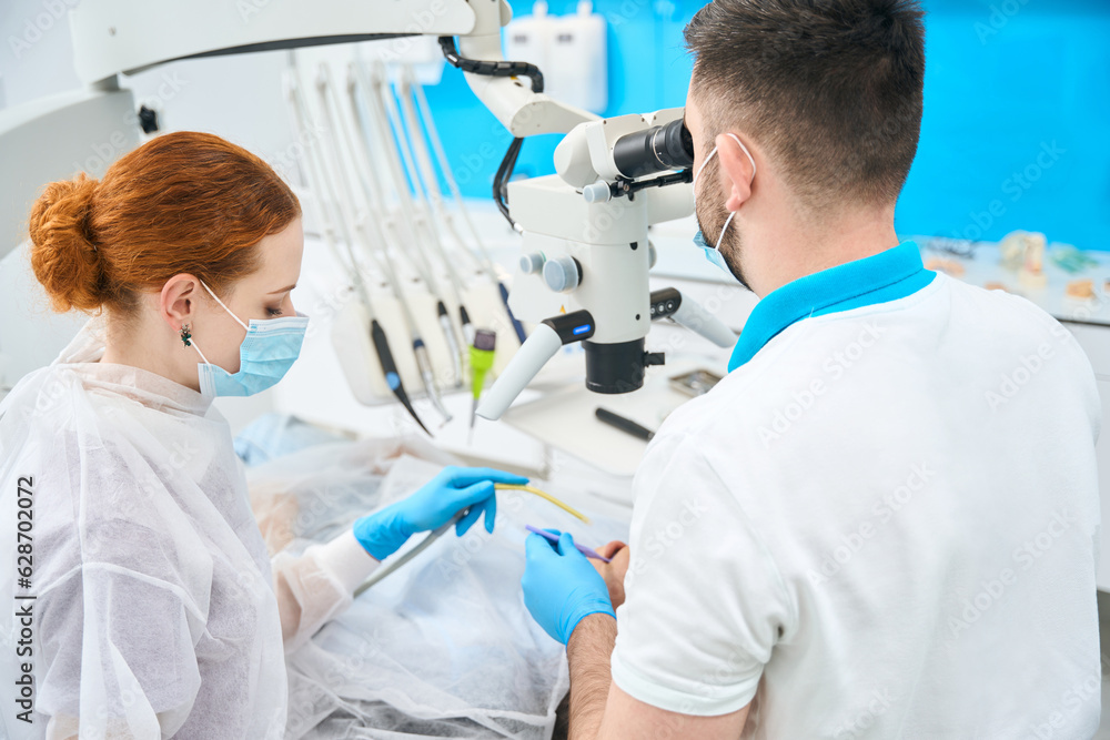 Doctor dentist and his red-haired assistant at their workplace Doctor dentist and his red-haired assistant at their workplace