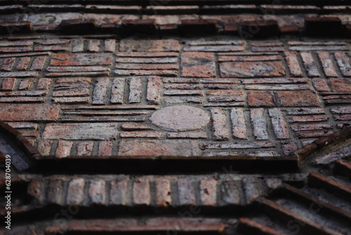 A brick wall has complex brickwork going vertically, horizontally, and at a curve, creating a richly textured image.